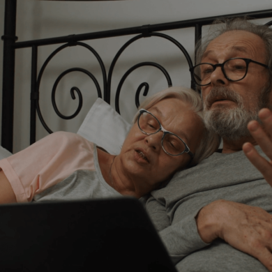 Old couple in bed using laptop.